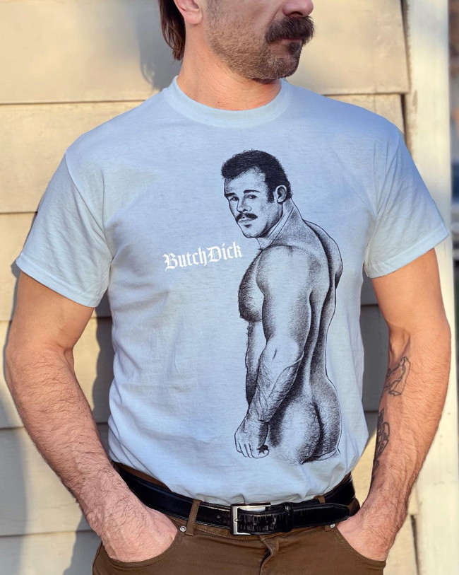 Man in moustache wears ButchDick Art T‑shirt showing naked moustachioed man turning to look at us